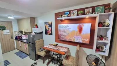 a kitchen with a table and a television on a wall at MOA Exquisite Suite Manila by JAO's Staycation in Manila
