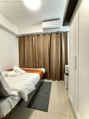 a bedroom with two beds and a curtain at New Oasis Staycation Shore 1 in Manila