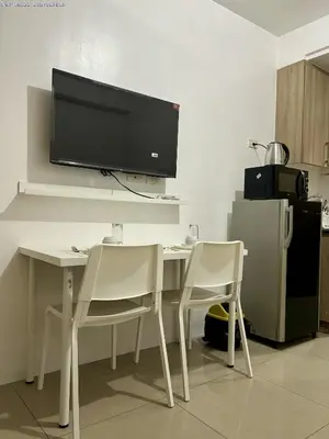 a desk with two chairs and a television on a wall at New Oasis Staycation Shore 1 in Manila