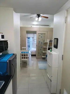 a kitchen with a ceiling fan and a living room at Homey 1 Bedroom Condo with Blacony and Wifi in Manila