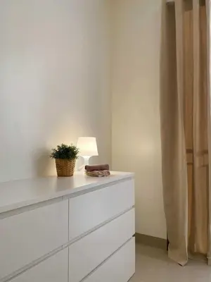 a white dresser with a lamp and a plant on it at Crystal Cove by Casa Stellar Mall of Asia Complex in Manila