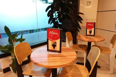 two tables and chairs with a menu on them at Hotel Sogo Dasmariñas Cavite in Dasmariñas
