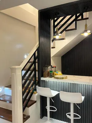 a kitchen with a counter and two white stools at Casa Estela in Binangonan