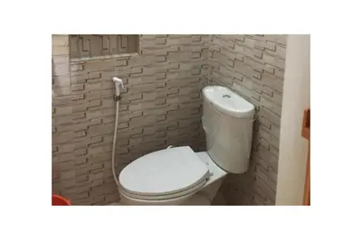 a bathroom with a white toilet in a brick wall at Collection O VIP Suites, Near PNR Pasay Evangelista, Makati Manila in Manila
