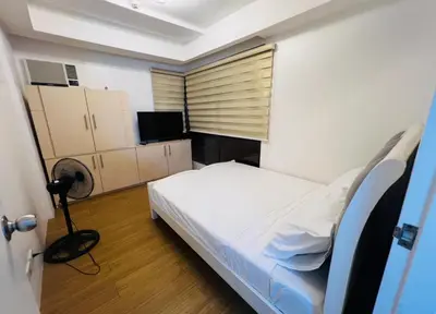 a small bedroom with a bed and a television at Porto Vita 2BR in Manila