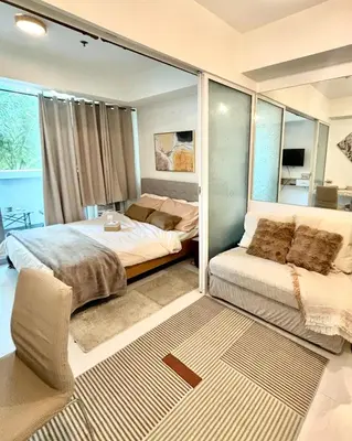 a bedroom with two beds and a mirror at Metroshore Azure 2 in Manila