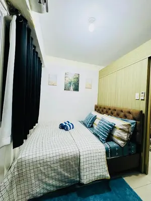 a bedroom with a bed with blue pillows at Shore Oasis Manila Near Mall of Asia in Manila