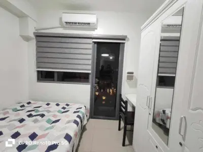 a bedroom with a bed and a desk and a window at Santorini Suite Manila-Mall of Asia in Manila