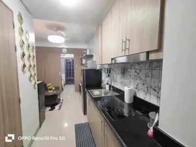 a kitchen with wooden cabinets and a black counter top at Santorini Suite Manila-Mall of Asia in Manila