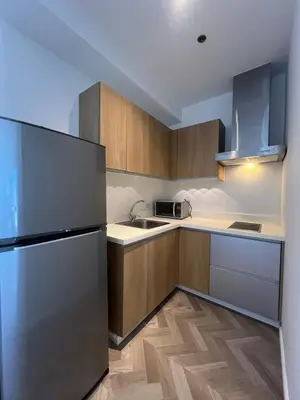 a kitchen with wooden cabinets and a stainless steel refrigerator at GRAMERCY - SKY-VIEW 1 Bed escape with POOL & SPA Access in Manila