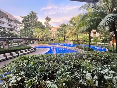 a swimming pool in a resort with palm trees and bushes at Siena Park by Casa Stellar Bicutan Paranaque in Manila