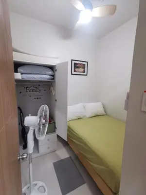 a small bedroom with a green bed and a fan at aldo shore 3 residence mall of asia in Manila