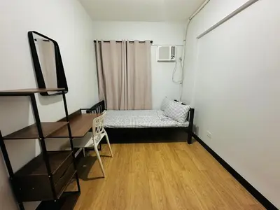 a room with a chair and a table and a mirror at Cozy 2-BR Perfect for Families and Friends in Manila