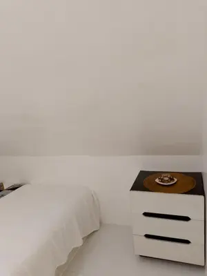 a white bedroom with a bed and a nightstand at Montalban Villa in General Trias