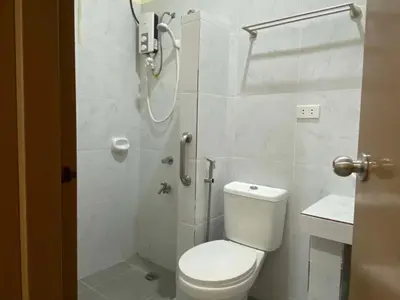 a white bathroom with a toilet and a shower at Home of Joy Villa Peace House in Dasmariñas