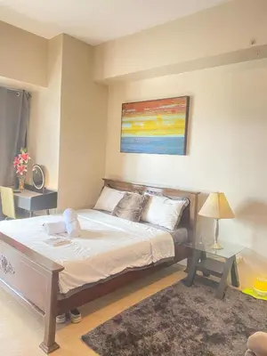 a bedroom with a bed and a painting on the wall at JOVYNOEL Condominium Unit Rental in Manila