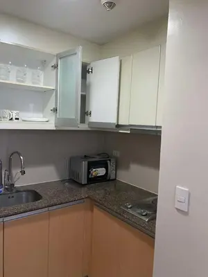 a kitchen with white cabinets and a sink and a microwave at JOVYNOEL Condominium Unit Rental in Manila