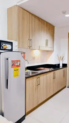 a kitchen with a white refrigerator and wooden cabinets at Shore Residences Moa Area Pasay City in Manila