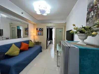 a living room with a blue couch and a table at Staycation Near Moa by Jen in Manila