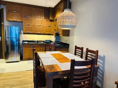 a kitchen with a wooden table with chairs and a chandelier at Cozy, Spacious 1 Bedroom Condo, reach St Lukes BGC by foot in Manila