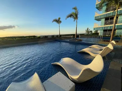 a swimming pool with white chairs and a building at Ultra Luxury 1BR near Solaire & Okada in Manila