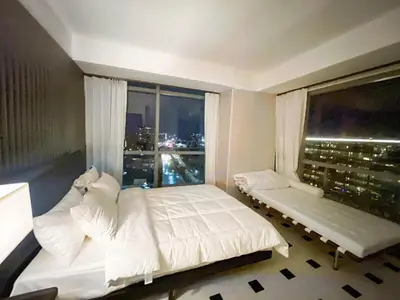 a bedroom with a white bed and a large window at Luxury 2BR Penthouse across City of Dreams in Manila