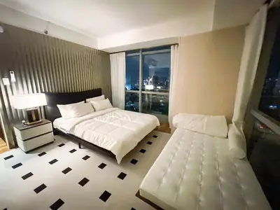 a bedroom with a large bed and a window at Luxury 2BR Penthouse across City of Dreams in Manila