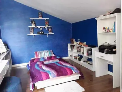 a bedroom with a blue wall with a bed and shelves at Our home is your castle in Caong