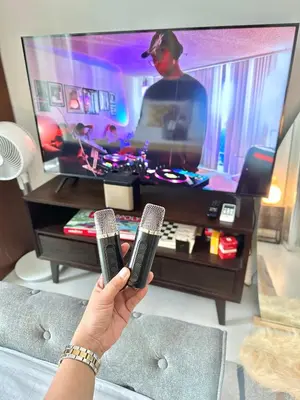 a person holding two microphones in front of a tv at Cityscape Staycation by H&B in Manila