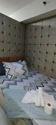 a bed with a headboard and a roll of toilet paper at Moana's Place Staycation in Manila