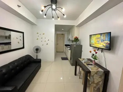 a living room with a couch and a table and a kitchen at MOA Complex Staycation in Manila