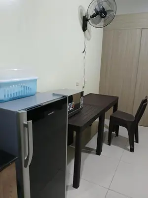 a kitchen with a black table and a fan at Breeze Residences in Manila