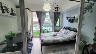 a bedroom with a bed and a large window at Jellybean's Snuggly Cabin in Manila
