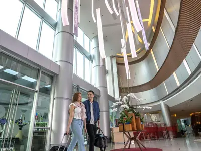 a couple walking through a shopping mall with their luggage at Novotel Manila Araneta City Hotel in Manila