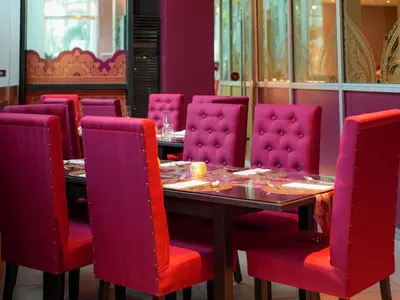 a dining room with a table and pink chairs at Novotel Manila Araneta City Hotel in Manila