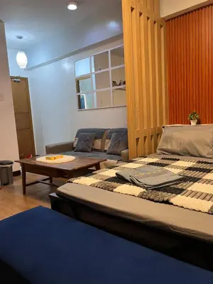 a room with a bed and a table and a couch at Mckinley Taguig Staycation in Manila