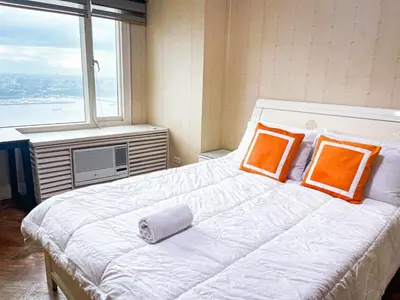 a bedroom with a bed with orange pillows and a window at Stunning & Luxury 4BR in Manila Bay White Beach in Manila