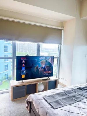 a bedroom with a flat screen tv in front of a window at Luxury 2BR Corner near Solaire & Okada II Sunset in Manila