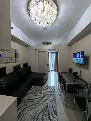 a living room with a black couch and a chandelier at Athalia's Pad at Sea Residences in Manila