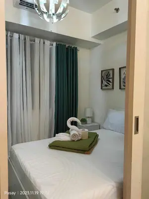 a bedroom with a white bed with a chandelier at Gab's Crib - Staycation near Mall of Asia in Manila