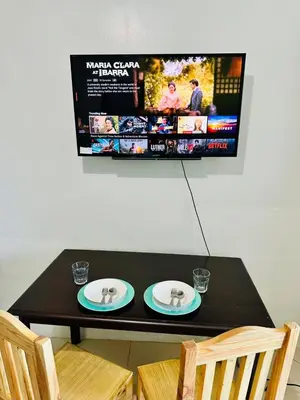 a table with two plates and a tv on the wall at Sea Residences by Sir Jan 0995-448-8872 in Manila