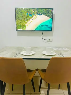 a table with two chairs and a tv on a wall at Sea Residences by Sir Jan 0995-448-8872 in Manila