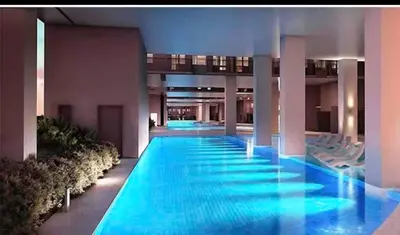 a large swimming pool in a building with blue water at Happy Sunshine at S Residences in Manila