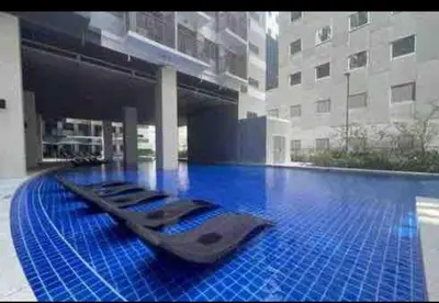 a swimming pool with a row of chaise lounges in a building at Happy Sunshine at S Residences in Manila