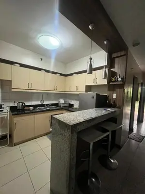 a large kitchen with a counter and a refrigerator at Arista Place Condo 2 bedroom unit in Manila