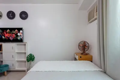 a bedroom with a bed and a clock on the wall at Makati Condo Near Airport & Greenbelt in Manila