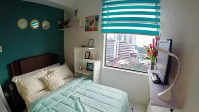 a bedroom with a bed and a window at Portovita Towers in Manila