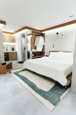 a bedroom with a large white bed and a green rug at The Kin House - Stay in Art Poblacion in Manila