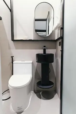 a bathroom with a white toilet and a mirror at The Kin House - Hotel in the Heart of Poblacion in Manila