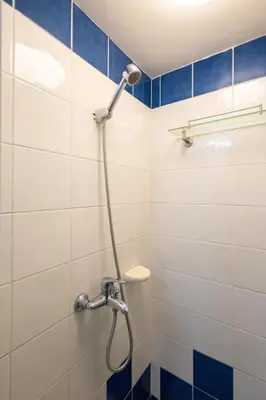 a shower in a bathroom with blue and white tiles at Charming Studio in Greenbelt Makati - Near Malls! in Manila